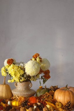 Şükran Günü geçmişi. Vazoda balkabağı ve kasımpatı, dökülen yapraklar, böğürtlen ve kozalaklar masada, yazı için yer var. Sonbahar hasadı hala hayattadır. Mutlu Şükran Günleri Sonbahar bayrağı