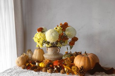 Şükran Günü geçmişi. Vazoda balkabağı ve kasımpatı, dökülen yapraklar, böğürtlen ve kozalaklar masada, yazı için yer var. Sonbahar hasadı hala hayattadır. Mutlu Şükran Günleri Sonbahar bayrağı