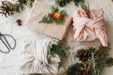 Sıfır atık Noel yatıyordu. Şık noel hediyeleri kumaş ve kağıda sarılmış, kır masasında köknar dalları ve doğal süsler. Kış çevre tatili, modern hediyeler. Mutlu Noeller.