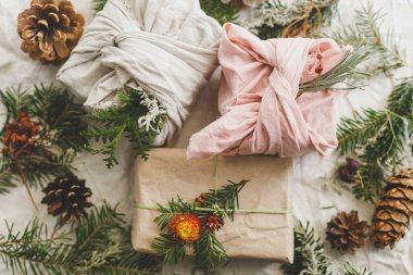 Sıfır atık Noel yatıyordu. Şık noel hediyeleri kumaş ve kağıda sarılmış, kır masasında köknar dalları ve doğal süsler. Kış çevre tatili, modern hediyeler. Mutlu Noeller.