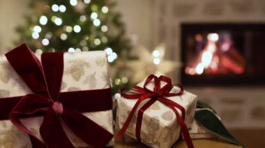  Şık noel hediyeleri ve arka planda süslü çelenk ışıkları ve yanan şömineli bir kedi. Evde atmosferik Noel arifesi. Evcil hayvanlı komik tatil görüntüleri