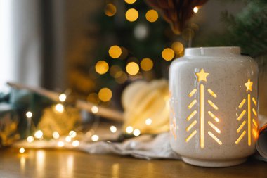 Şık bir yılbaşı feneri, hediye ve modern kağıt süslemeleri, arka plandaki rustik masa üzerinde Noel ağacı ışıkları. Mutlu Noeller! Atmosferik Noel zamanı, bayram afişi