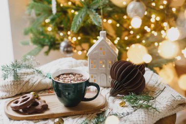 Noel Hygge 'ı. Şekerlemeli ve kurabiyeli sıcak çikolata, noel süsleri, rahat örülmüş süveter ve altın ışıklarla süslenmiş şık ağaçlara karşı köknar dalları. Kış sancağı