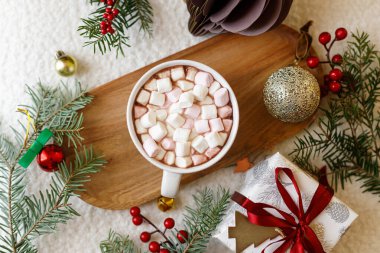 Noel yatağı. Bir fincan sıcak çikolata, marşmelov, noel süsleri ve hediye, rahat örülmüş süveter ve köknar dalları. Mutlu noeller. Kış kızlık zarı