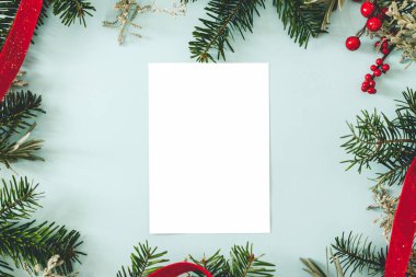 Boş tebrik kartı ve köknar dalları, mavi arka planda kırmızı böğürtlenler. Mesaj atmak için yeri olan bir Noel kartı modeli. Xmas kartpostalı. Mevsim tebrik kartı şablonu