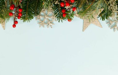Noel yatağı. Yeşil köknar dalları, kırmızı böğürtlen ve açık mavi arkaplanda klasik süsler. Mutlu noeller. Yılbaşı sınırını mesaj için kullanacağız. Xmas arkaplanı