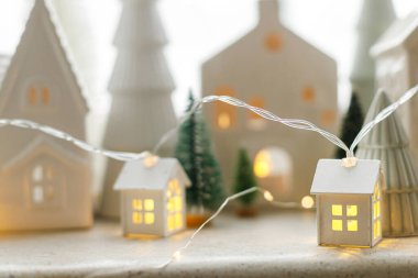 Mutlu Noeller! Beyaz evleri, ağaçları ve altın ışıklarıyla karlı camları olan şık bir Noel tatil köyü. Atmosferik büyülü sahne. Noel bayrağı.