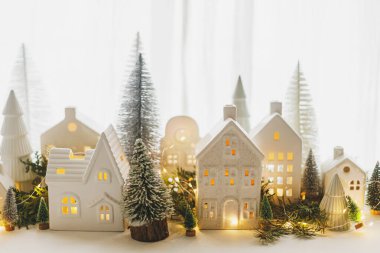 Mutlu Noeller! Şık bir Noel minyatür tatil köyü. Akşamları evleri, ağaçları ve altın ışıklarıyla pencereleri tıkanır. Atmosferik büyülü sahne. Noel bayrağı.