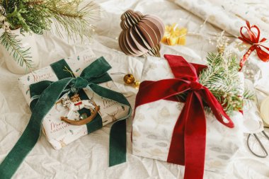 Mutlu Noeller ve mutlu tatiller. Kırmızı ve yeşil kurdeleli şık Noel hediyeleri, köknar dalları, eski oyuncaklar ve kırsal masadaki modern süsler. Paketlenmiş Noel hediyeleri, bayram afişleri