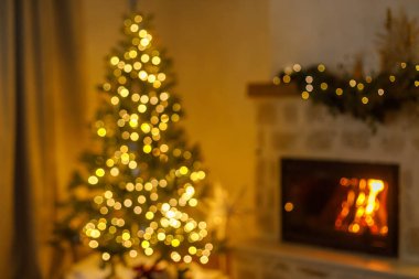 Mutlu Noeller! Altın ışıklarla süslenmiş şık bir Noel ağacı ve akşam oturma odasında yanan bir şömine. Evde atmosferik noel arifesinde odaklanamamak. Xmas arkaplanı