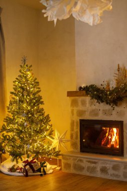 Şık bir Noel ağacı, klasik mücevherleri ve altın ışıklarıyla modern oturma odasında şömine şöminesi ile süslenmiş. Şenlikli Xmas İskandinav odası. Atmosfer sihirli arifesi