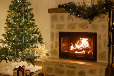 Mutlu Noeller! Şık dekore edilmiş yılbaşı ağacı, eski süsler ve şömine rafının modern dekorasyonuyla akşamları çan, kurdele ve çelenk ışıkları. Evde atmosferik Noel arifesi