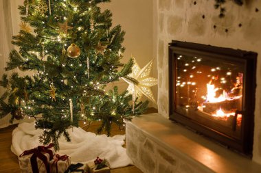 Şık bir Noel ağacı, klasik mücevherleri ve altın ışıklarıyla modern oturma odasında şömine şöminesi ile süslenmiş. Şenlikli Xmas İskandinav odası. Atmosfer sihirli arifesi