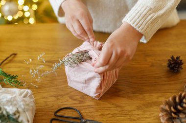 Ahşap masanın üzerinde köknar dalı olan keten kumaşa sarılmış eller. sıfır israf noeli