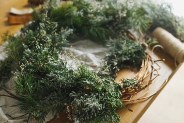 Şık, sade bir Noel çelengi yapıyorum. Çevreci dallar, dallar, sicim, makas atmosferik festival odasında kırsal masada. Kış tatili hazırlıkları, ayrıntılar