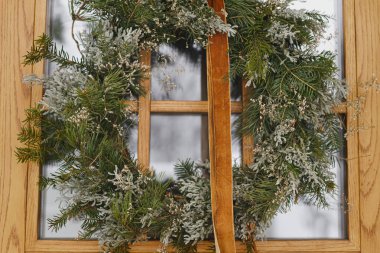 Ön kapısında kurdele asılı, şık bir Noel rustik çelengi. Kapatın. Modern ev girişi ya da kış tatili için veranda dekorasyonu. Mutlu Noeller ve mutlu tatiller