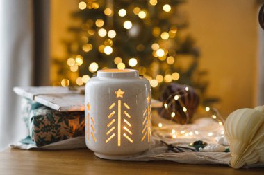 Mutlu Noeller ve mutlu Noeller! Şık bir Noel hediyesi, parlayan bir fener, altın Noel ağacı ışıklarına karşı masanın üstünde modern kağıt süsler. Atmosferik Noel arifesi, büyülü tatil zamanı.