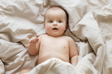 Sabahın köründe bej çarşaflarda yatan şirin bir bebek. Yatma vakti. Uykudan sonra mutlu bebek portresi, yazı için yeri olan üst manzara. Çocukluk ve çocuk bakımı