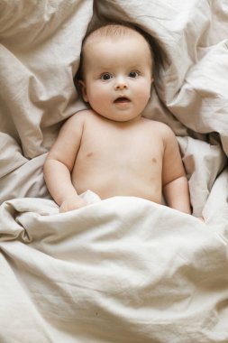 Sabahın köründe bej çarşaflarda yatan şirin bir bebek. Yatma vakti. Uykudan sonra mutlu bebek portresi, yazı için yeri olan üst manzara. Çocukluk ve çocuk bakımı