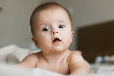Yatakta uzanmış şirin bir bebek. Yatma vakti ya da sabah uyanın. Komik duygularla dolu mutlu bebek portresi, mesaj için yer. Çocukluk ve çocuk bakımı