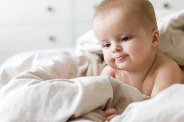 Bej çarşaflı şirin bir bebek. Ya uyuma ya da uyanma vakti. Yatakta bebek portresi, mesaj için yer. Çocuk uykusu ve çocuk bakımı