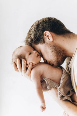 Babalar Günün kutlu olsun! Havalı bir baba beyaz duvara karşı öpüşüyor ve küçük şirin bir çocuğa sarılıyor. Babalık ve ebeveynlik. Evlat edinme ve doğurganlık kavramı
