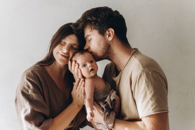 Mutlu anne ve baba küçük oğlunu kucaklıyor ve öpüyor. Anneler günün kutlu olsun ve babalar günün kutlu olsun! Annelik ve ebeveynlik. Evlat edinme ve doğurganlık kavramı