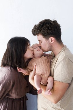 Mutlu anne ve baba öpüşüyor ve küçük oğluna sarılıyor. Anneler günün kutlu olsun ve babalar günün kutlu olsun! Annelik ve ebeveynlik. Evlat edinme ve doğurganlık kavramı