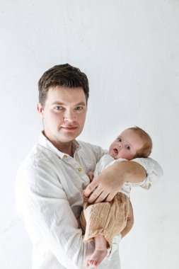 Şık bir baba, küçük oğluna sarılıp beyaz duvara yaslanıyor. Babalar Günün kutlu olsun, babalık ve ebeveynlik. Evlat edinme ve doğurganlık kavramı