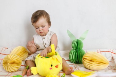 Paskalya bebeğinin paskalya sepetindeki renkli yumurta ve havuçlarla oynaması. Sevimli Paskalya tavşanı ve Paskalya avı konsepti. Mutlu Paskalyalar