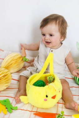 Paskalya bebeğinin paskalya sepetindeki renkli yumurta ve havuçlarla oynaması. Sevimli Paskalya tavşanı ve Paskalya avı konsepti. Mutlu Paskalyalar