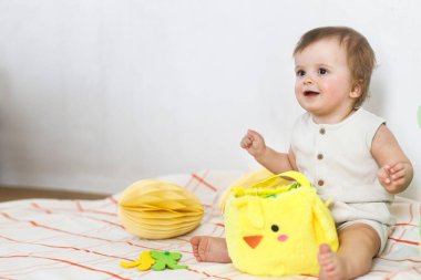 Mutlu Paskalyalar! Renkli paskalya kağıtlı yumurtaları, sepeti, şenlikli dekorasyonu ve havuçları olan şirin bir bebek. Sevimli Paskalya tavşanı ve Paskalya avı.