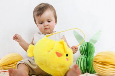 Paskalya bebeğinin paskalya sepetindeki renkli yumurta ve havuçlarla oynaması. Sevimli Paskalya tavşanı ve Paskalya avı konsepti. Mutlu Paskalyalar