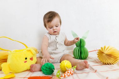 Paskalya bebeğinin paskalya sepetindeki renkli yumurta ve havuçlarla oynaması. Sevimli Paskalya tavşanı ve Paskalya avı konsepti. Mutlu Paskalyalar