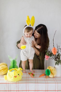 Mutlu Paskalyalar! Sevimli bebek tavşancık ve mutlu anne renkli paskalya kâğıdı yumurtaları, şenlikli dekorasyon ve havuçlarla birlikte oynuyorlar. Sevimli Paskalya tavşanı ve Paskalya avı.