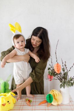 Mutlu Paskalyalar! Sevimli bebek tavşancık ve mutlu anne renkli paskalya kâğıdı yumurtaları, şenlikli dekorasyon ve havuçlarla birlikte oynuyorlar. Sevimli Paskalya tavşanı ve Paskalya avı.