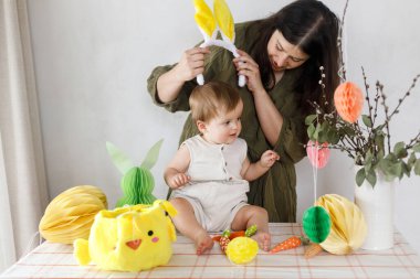 Mutlu Paskalyalar! Sevimli bebek ve mutlu anne renkli paskalya kâğıdı yumurtaları, şenlikli dekorasyon ve havuçlarla dekore ediyorlar. Sevimli Paskalya tavşanı ve Paskalya avı.