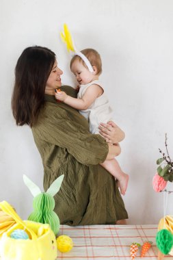 Mutlu Paskalyalar! Sevimli bebek tavşancık ve mutlu anne renkli paskalya kâğıdı yumurtaları, şenlikli dekorasyon ve havuçlarla sarılıp oynuyorlar. Sevimli Paskalya tavşanı ve Paskalya avı.