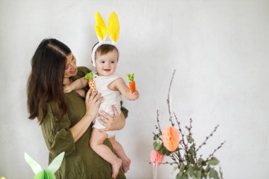 Mutlu Paskalyalar! Sevimli bebek tavşancık ve mutlu anne renkli paskalya kâğıdı yumurtaları, şenlikli dekorasyon ve havuçlarla sarılıp oynuyorlar. Sevimli Paskalya tavşanı ve Paskalya avı.