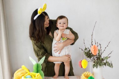 Mutlu Paskalyalar! Sevimli bebek ve mutlu anne renkli paskalya kâğıdı yumurtaları, şenlikli dekorasyon ve havuçlarla birlikte oynuyorlar. Sevimli Paskalya tavşanı ve Paskalya avı.