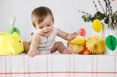 Paskalya bebeğinin paskalya sepetindeki renkli yumurta ve havuçlarla oynaması. Sevimli Paskalya tavşanı ve Paskalya avı konsepti. Mutlu Paskalyalar