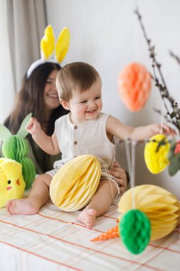 Mutlu Paskalyalar! Sevimli bebek ve mutlu anne renkli paskalya kâğıdı yumurtaları, şenlikli dekorasyon ve havuçlarla birlikte oynuyorlar. Sevimli Paskalya tavşanı ve Paskalya avı.