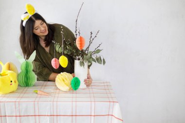 Mutlu Paskalyalar! Tavşan kulaklı şık bir kadın renkli paskalya yumurtaları, tavşanlar ve havuçlarla süslüyor. Paskalya sofrası kurma ve Paskalya avı.