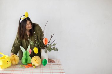 Mutlu Paskalyalar! Tavşan kulaklı şık bir kadın renkli paskalya yumurtaları, tavşanlar ve havuçlarla süslüyor. Paskalya sofrası kurma ve Paskalya avı.
