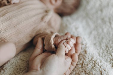 Anneler Günün kutlu olsun! Babalar Günün kutlu olsun! Ebeveynler yeni doğmuş bebeklerin elini sıkıca tutuyor. Aşk ve aile kavramı. Anne ve baba küçük tatlı bebekle kaynaşıyor. Evlat edinme ve bakım