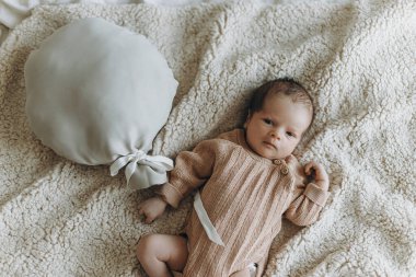 Yeni doğmuş şirin bebek, balon oyuncağıyla battaniyeye uzanmış. Örülmüş giysiler içinde küçük tatlı bir bebek yatakta yatıyor. Üstü açık, yazı için yeri var. Evlat edinme. Çocuk sağlığı ve cilt bakımı kavramı