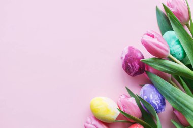 Mutlu Paskalyalar! Pembe laleli renkli Paskalya yumurtaları pembe arka planda düz bir sınır çiziyor, mesaj için boşluk. Paskalya bayrağı, poster şablonu