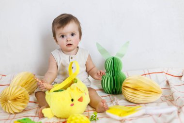 Paskalya bebeğinin paskalya sepetindeki renkli yumurta ve havuçlarla oynaması. Sevimli Paskalya tavşanı ve Paskalya avı konsepti. Mutlu Paskalyalar