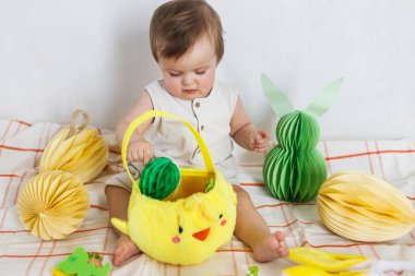 Paskalya bebeğinin paskalya sepetindeki renkli yumurta ve havuçlarla oynaması. Sevimli Paskalya tavşanı ve Paskalya avı konsepti. Mutlu Paskalyalar