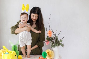 Mutlu Paskalyalar! Sevimli bebek tavşancık ve mutlu anne renkli paskalya kâğıdı yumurtaları, şenlikli dekorasyon ve havuçlarla birlikte oynuyorlar. Sevimli Paskalya tavşanı ve Paskalya avı.